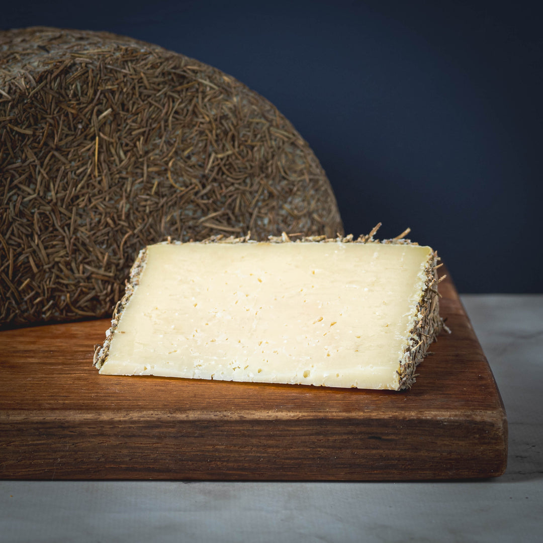 Oveja al Romero sheep cheese from Spain on a wooden board with a dark background